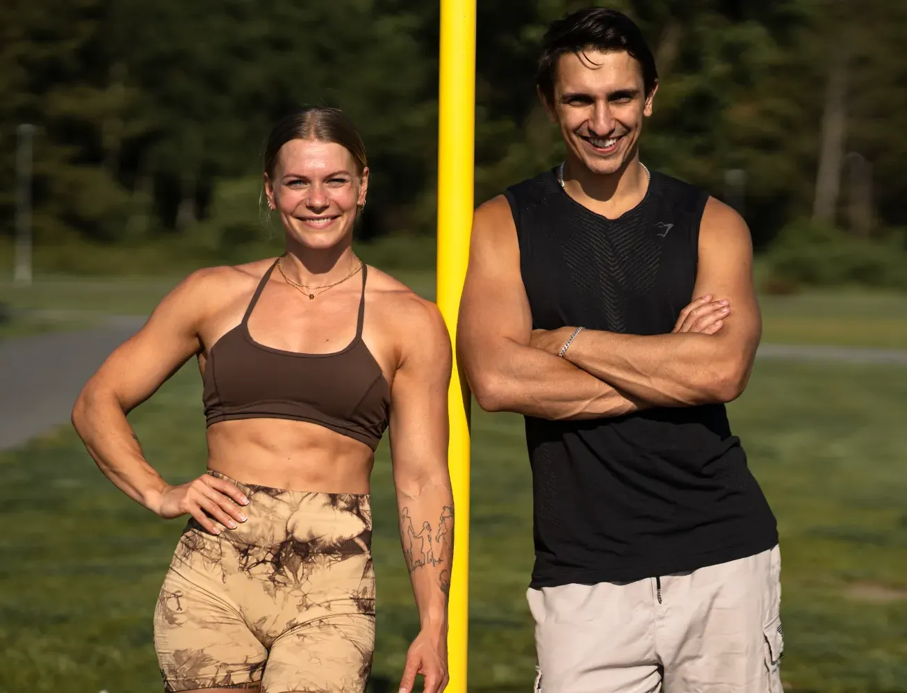 Two people smiling and posing together in an outdoor fitness setting