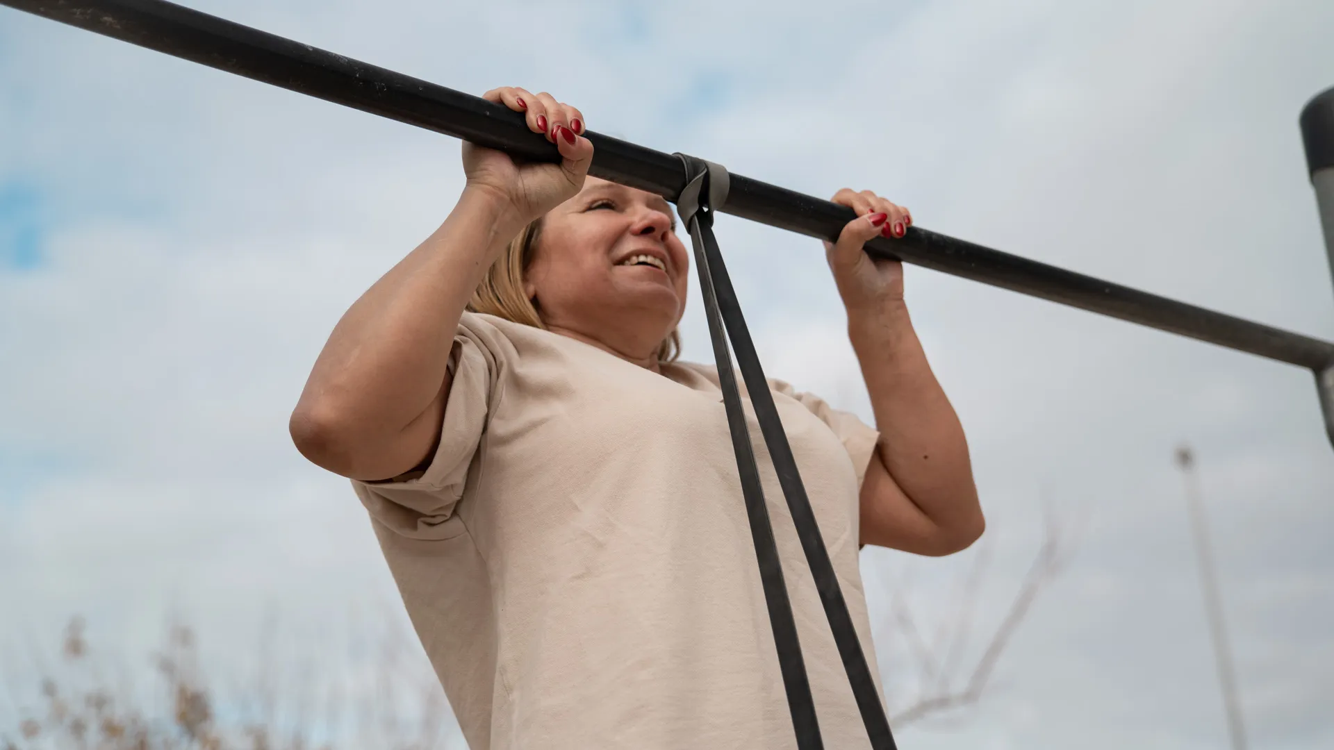 This image features a woman performing an assisted pull-up with a resistance band attached to the pull-up bar.
