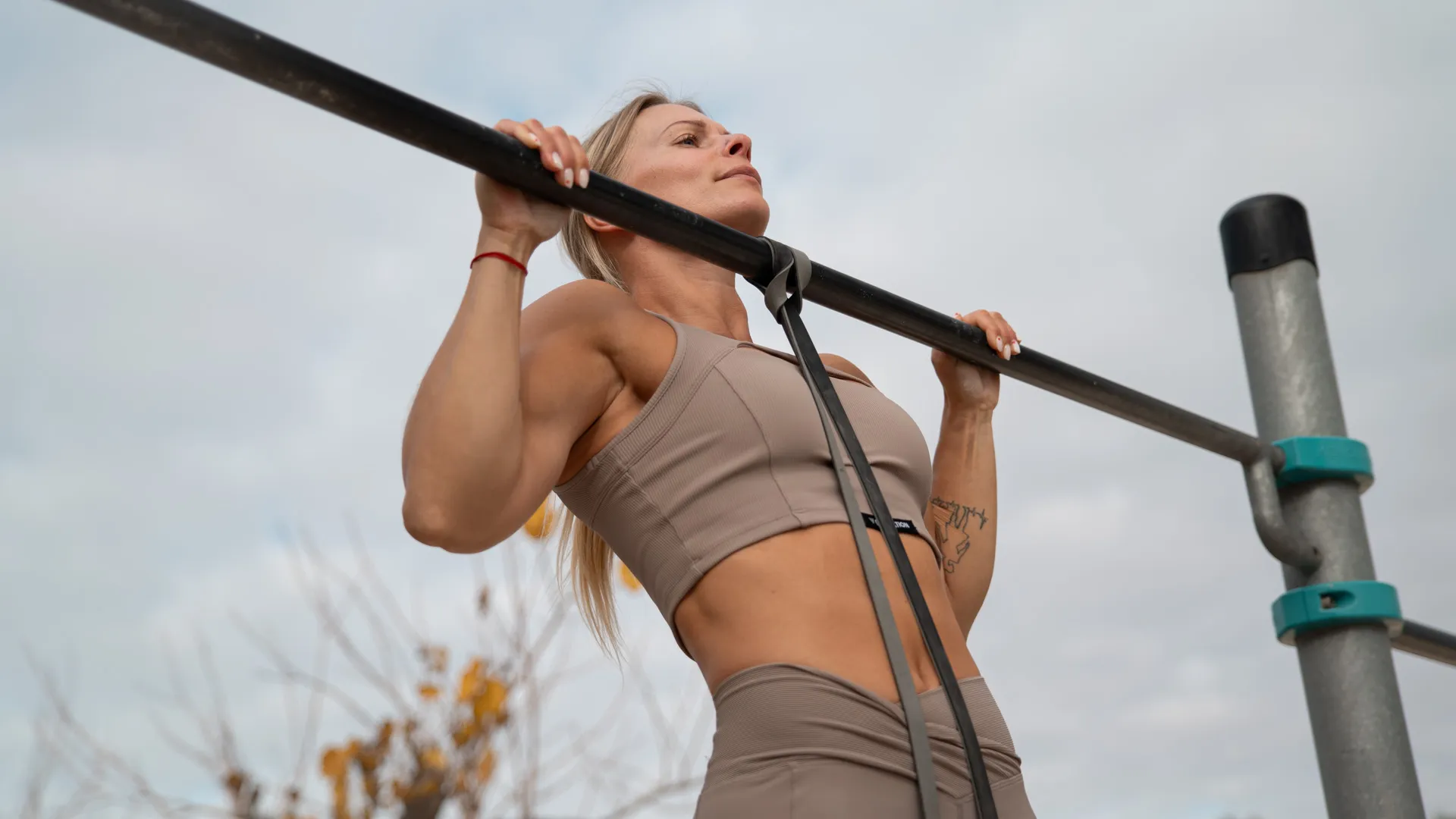 Bilden visar en person som utför en assisterad pull-up på en utomhus-pull-up-stång med ett motståndsband.