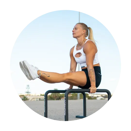 Kvinna som utför en calisthenics-rörelse på paralletter med benen sträckta fram i L-sit-position.