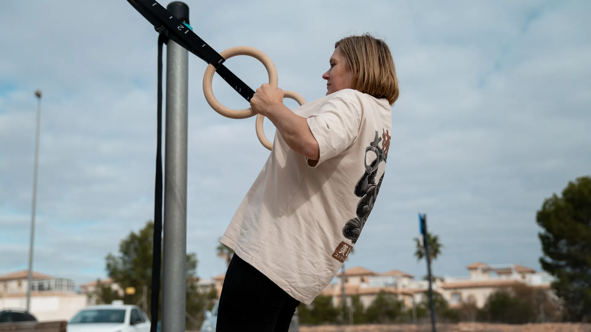 This image showcases an individual performing an assisted ring row using gymnastic rings. This exercise is excellent for developing upper body pulling strength, particularly targeting the back and arms, while also engaging the core. The individual leans back and pulls their body toward the rings, a scalable movement suitable for beginners. Adjusting the angle of the body relative to the ground changes the difficulty—standing more upright makes it easier, while leaning further back increases the challenge. This exercise is a great introduction to pull-up progressions.