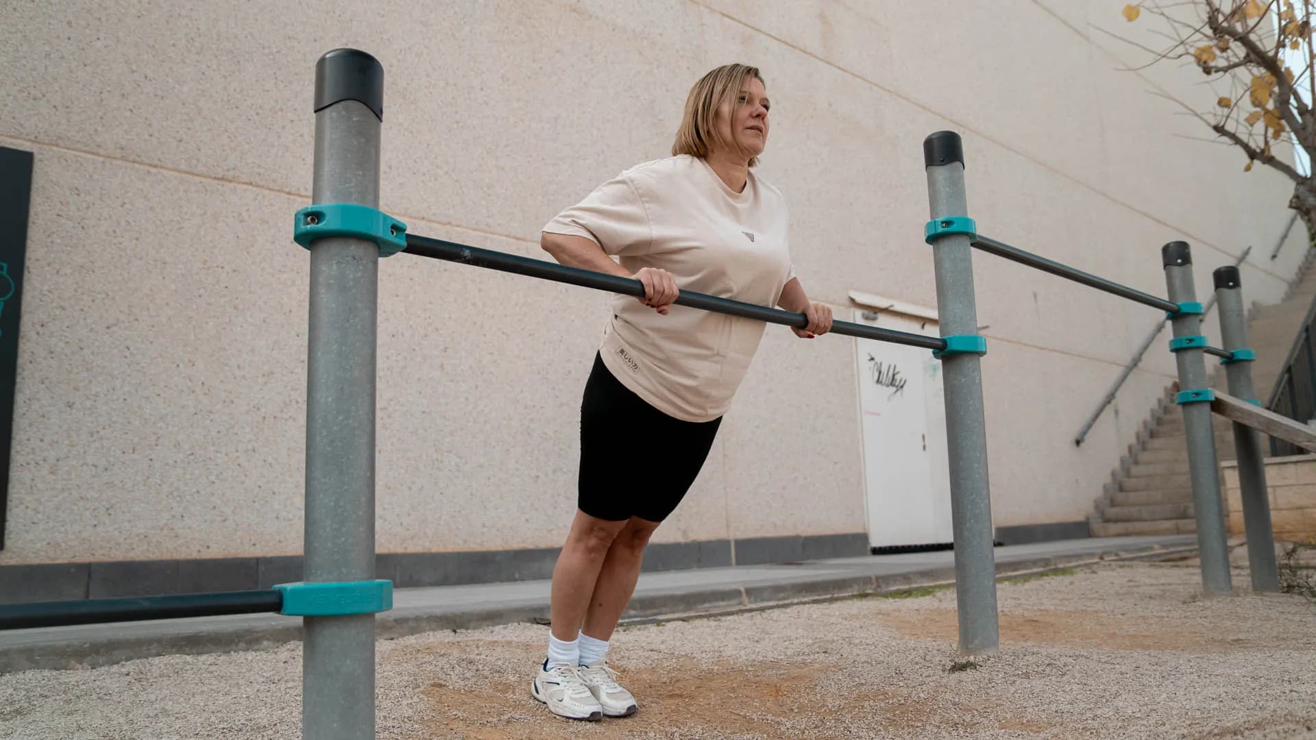 A woman practicing incline rows on a low bar outdoors.